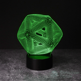 A green illuminated 3D lamp in the shape of an icosahedron, a geometric form composed of twenty triangular surfaces, displayed on a black base against a dark background. This functions as both a unique study aid and a contemporary office lamp option in Australia.