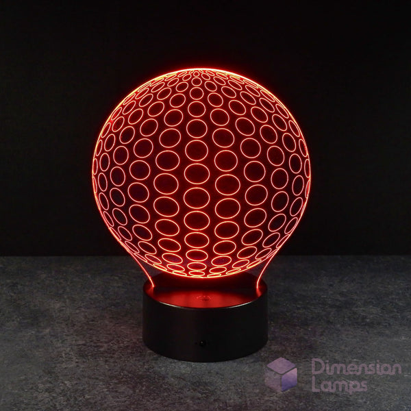 A 3D illusion lamp presenting a symmetrical pattern of radiating circles forming a sphere, illuminated in red, resting on a black base against a dark background. Its symmetry makes for a great study aid.