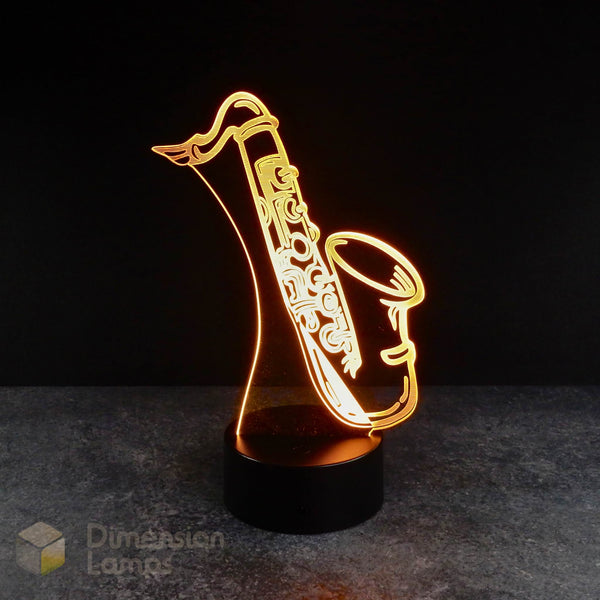 3D LED illusion lamp in the shape of a saxophone, illuminated with a warm light, placed on a black surface. Saxophone fan gift idea.