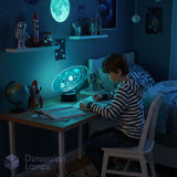 Child sitting at a desk in a dark room with a galaxy lamp, surrounded by space-themed decor.